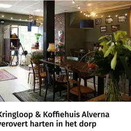 Gezellige eethoek met houten tafels en stoelen, planten en foto's aan de wand