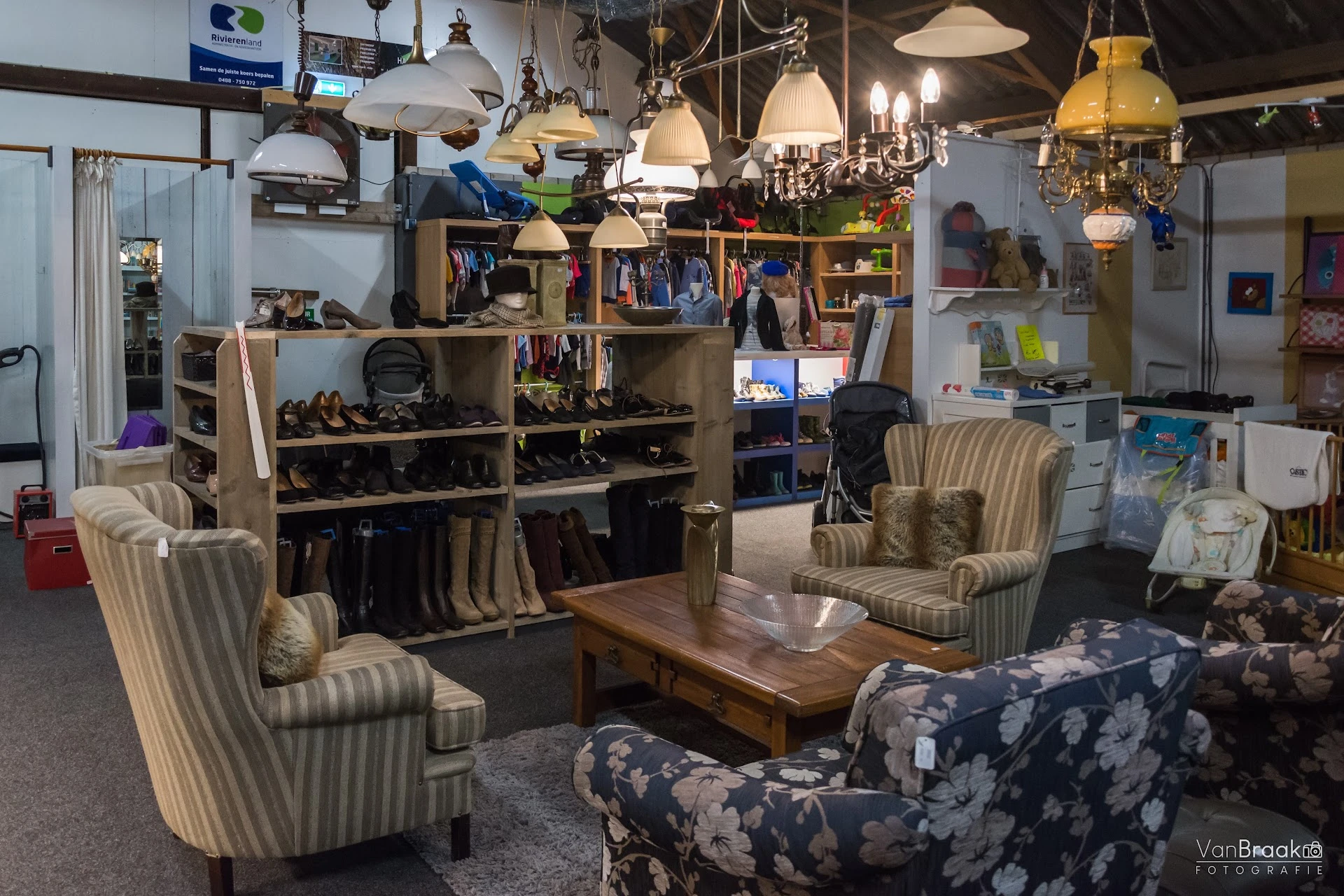 Winkelvloer met gezelzithoeken, stellingen met schoenen en boeken, vintage hanglampen aan plafond