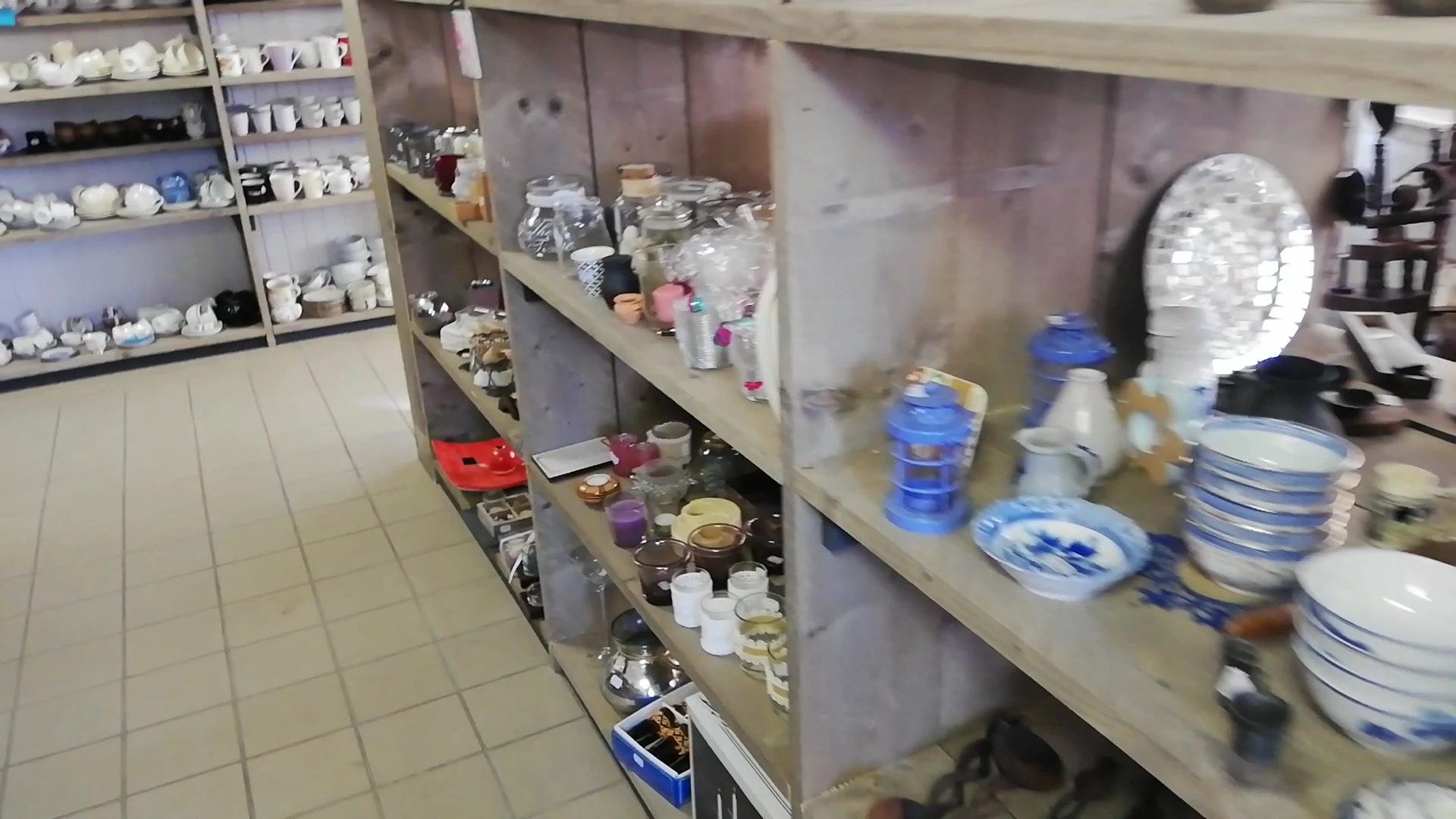 Stellingen met diverse huishoudelijke items zoals serviesgoed, glazen en decoratieve voorwerpen