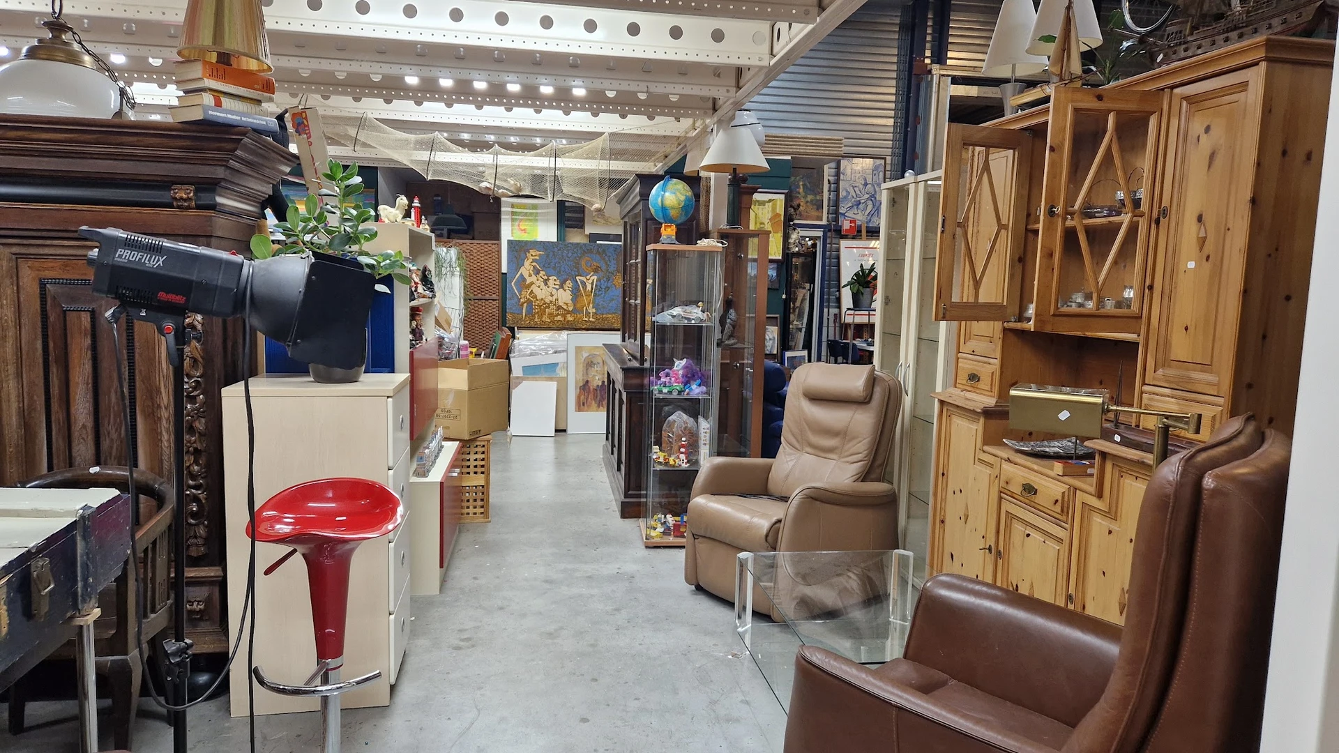 Winkelvloer van kringloopwinkel met meubels, kasten, fauteuils en diverse artikelen langs de zijkanten