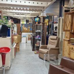 Winkelvloer van kringloopwinkel met meubels, kasten, fauteuils en diverse artikelen langs de zijkanten