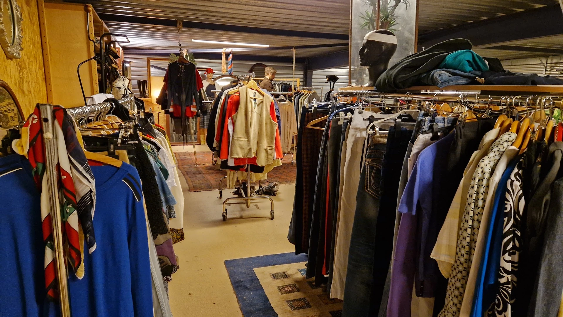 Winkelvloer met kledingrekken vol tweedehands kleding, etalagepoppen en winkelinterieur