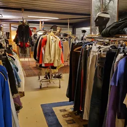 Winkelvloer met kledingrekken vol tweedehands kleding, etalagepoppen en winkelinterieur