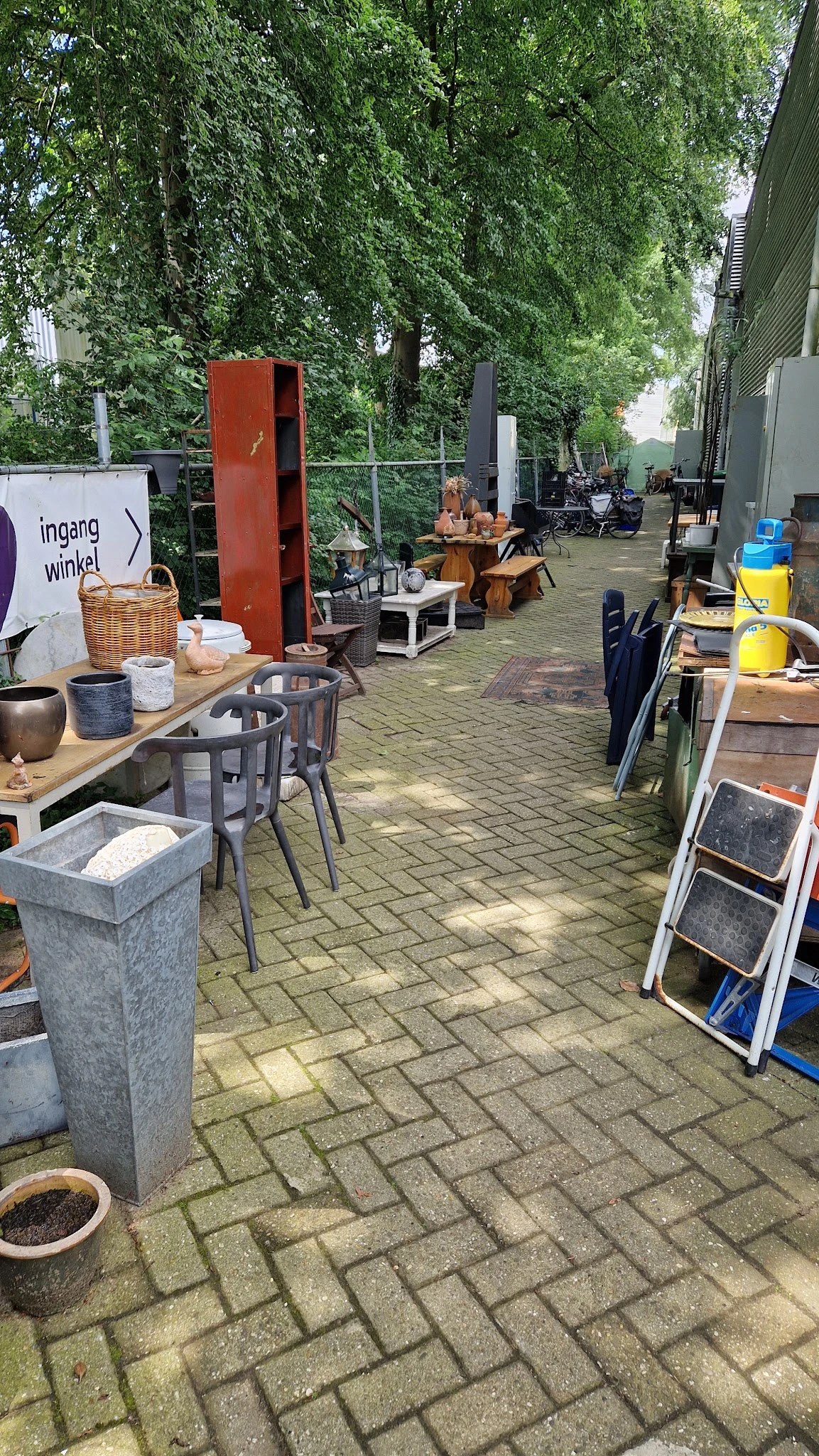 Overdekt terras met tafels, stoelen en diverse spullen in een kringloopwinkel