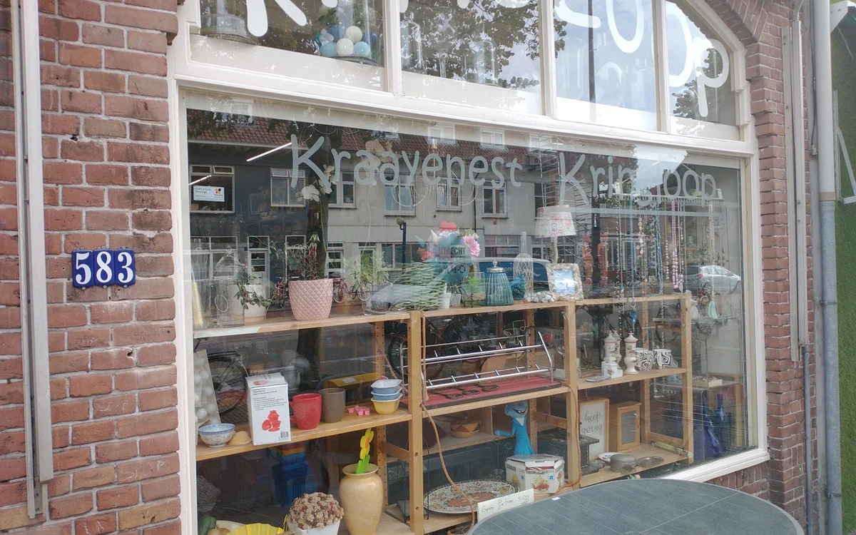 Winkelruit van Kraayenest Kringloop met huisnummer 583, stellingen met diverse spullen zichtbaar in de etalage
