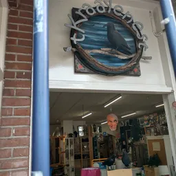 Winkelraam met blauw frame en decoratieve vis boven de ingang, man zichtbaar in winkelinterieur