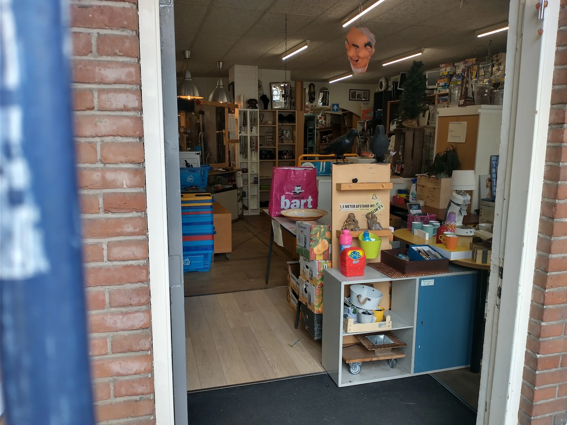 Winkelvloer van kringloopwinkel met diverse spullen, stellingen en artikelen op toonbank