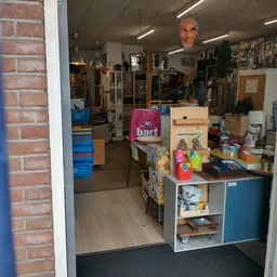 Winkelvloer van kringloopwinkel met diverse spullen, stellingen en artikelen op toonbank