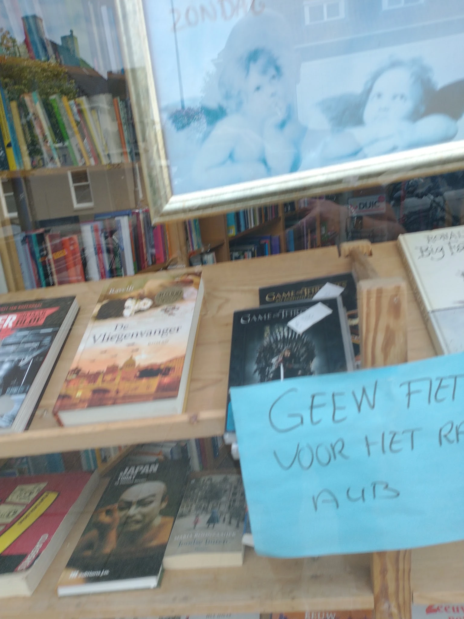 Boeken en dvd's uitgestald in dozen op een tafel met een blauw notitiebord