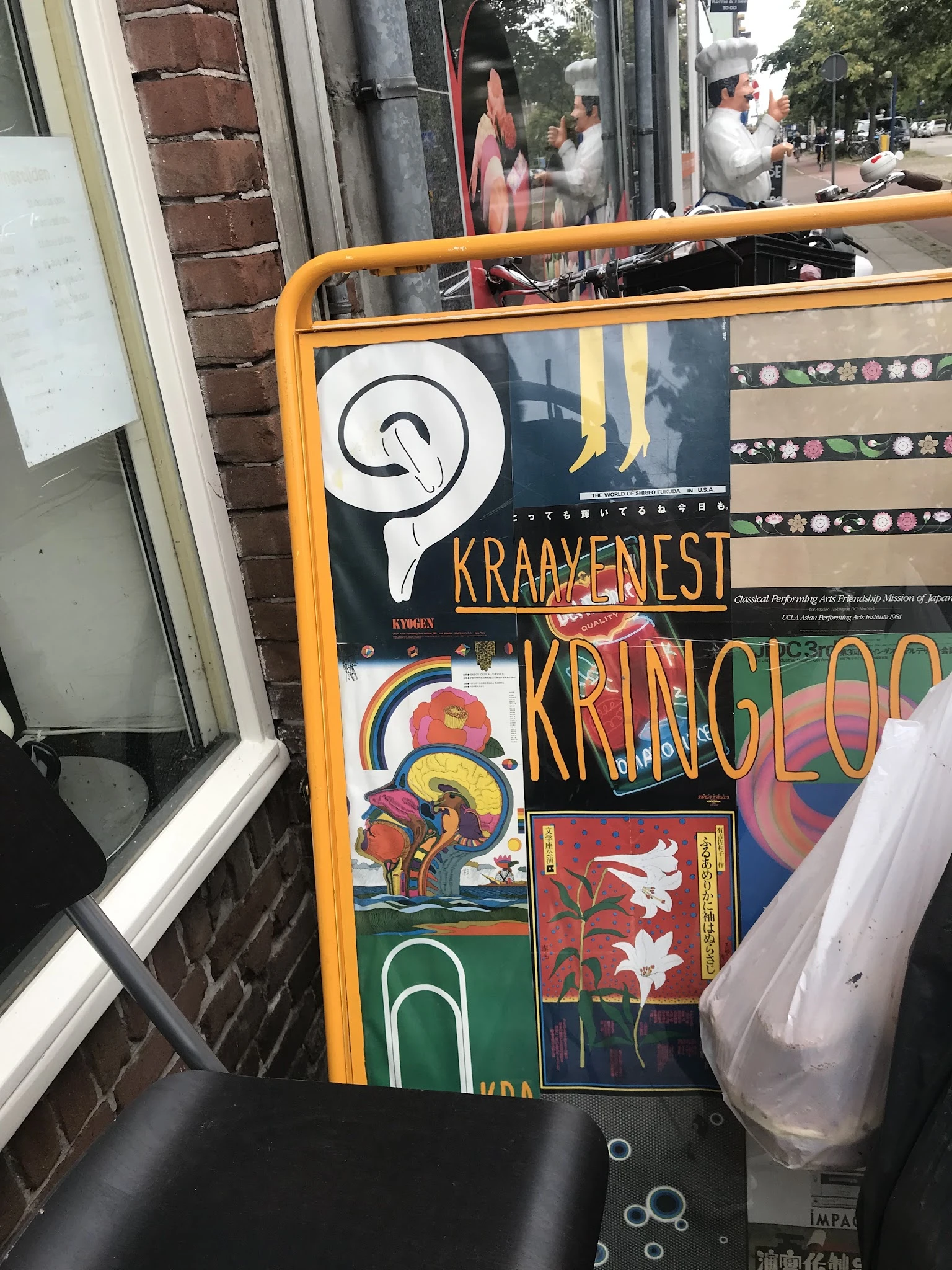 Verzameling van vintage posters en kunstwerken tegen een oranje kader, waaronder werk van Kraayenest