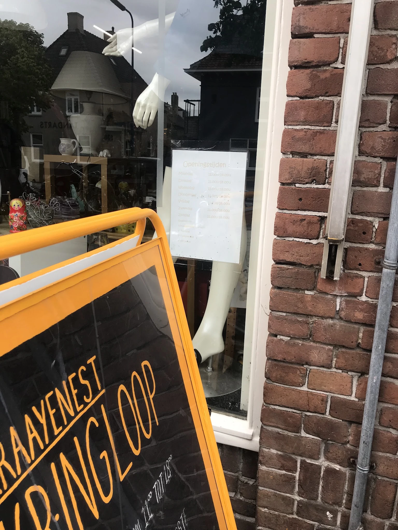 Voorkant van kringloopwinkel met oranje A-bord en bakstenen gevel