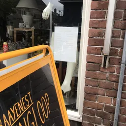 Voorkant van kringloopwinkel met oranje A-bord en bakstenen gevel