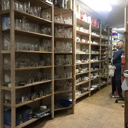 Stellingen met glazen serviesgoed en huishoudartikelen in een kringloopwinkel