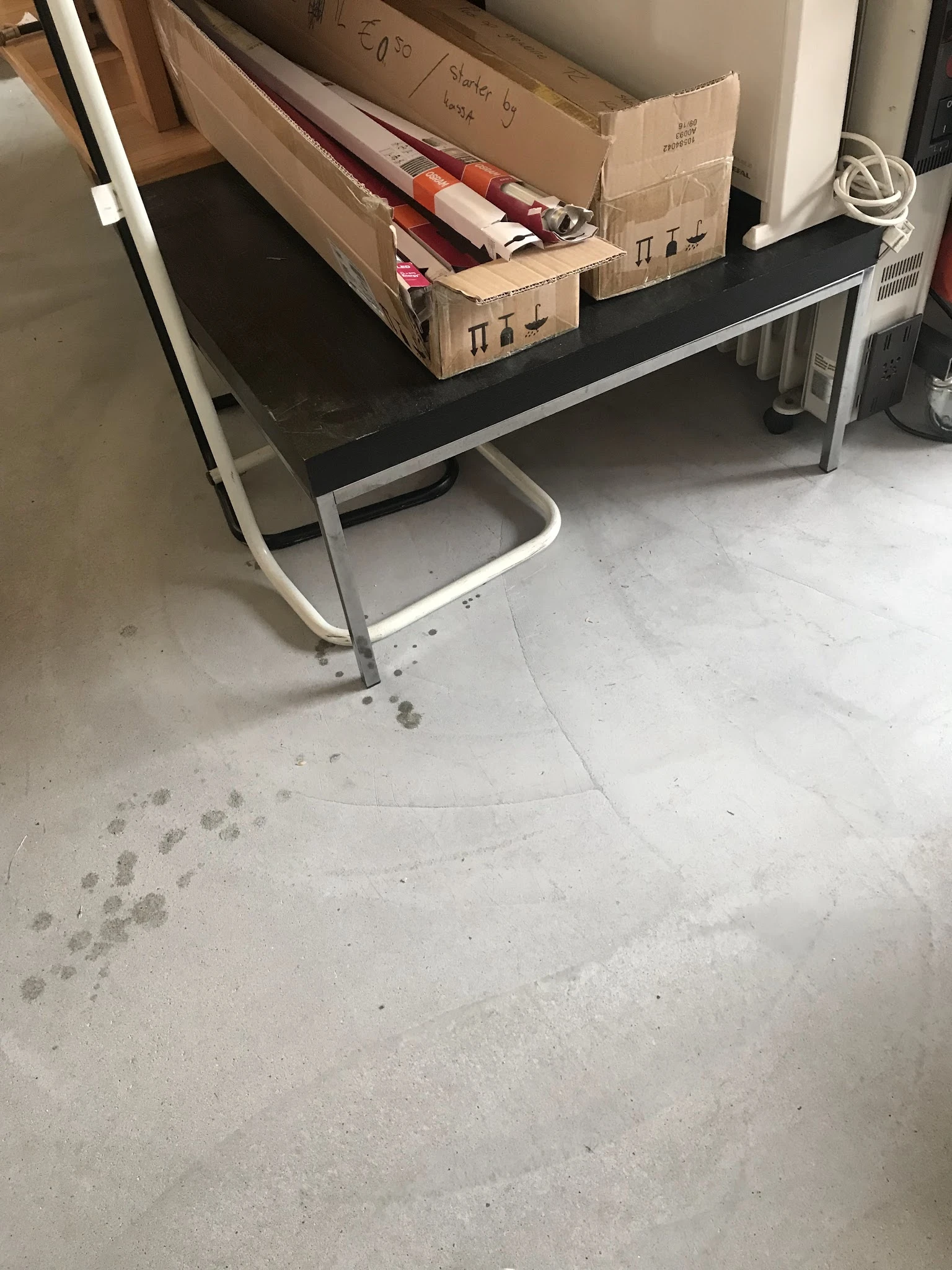 Betonnen winkelsvloer met voetafdrukken en een tafel met witte poten