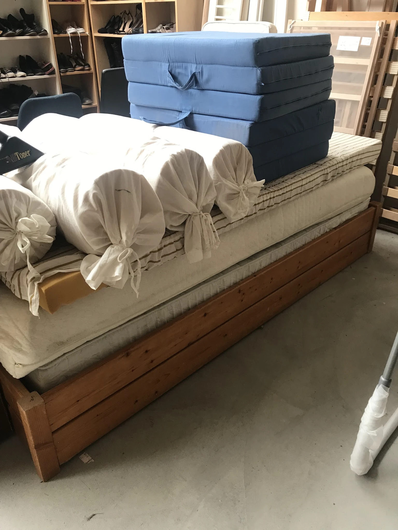 Tweepersoonsmatras met witte lakens en decoratieve kussens op houten bedframe