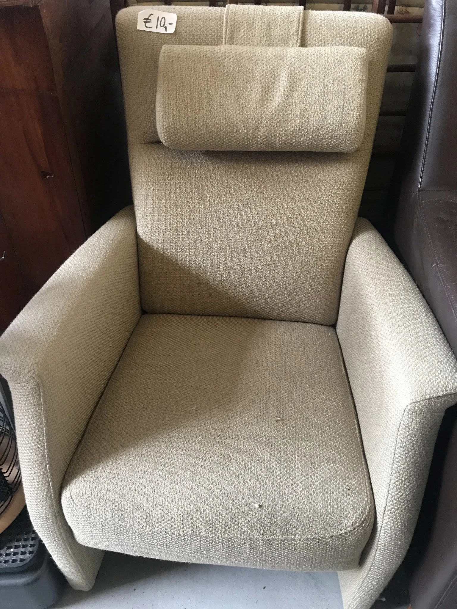 Crèmekleurige fauteuil met hoge rugleuning en armleuningen, close-up van voorkant