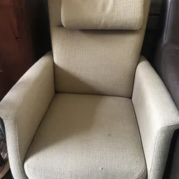Crèmekleurige fauteuil met hoge rugleuning en armleuningen, close-up van voorkant