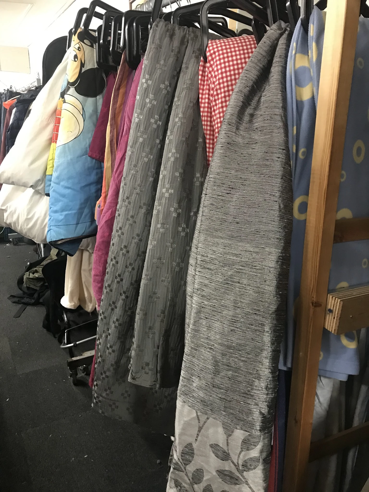 Rekken met tweedehands kleding in verschillende kleuren en patronen