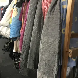 Rekken met tweedehands kleding in verschillende kleuren en patronen