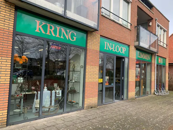 Groene gevel van kringloopwinkel met etalages en naam KRING-IN-LOOP zichtbaar