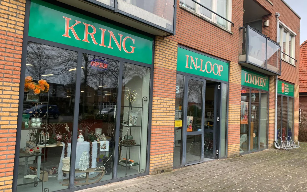 Groene gevel van kringloopwinkel met etalages en naam KRING-IN-LOOP zichtbaar