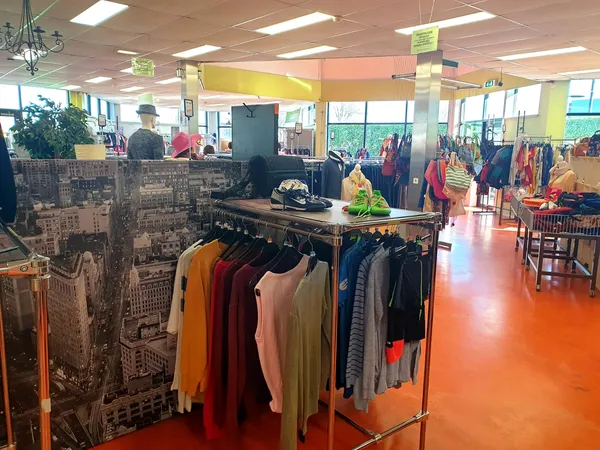 Winkelvloer met kledingrekken en uitgestalde artikelen in een kringloopwinkel