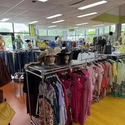 Winkelvloer met kledingrekken, mannequins en kleding in een kringloopwinkel met grote ramen