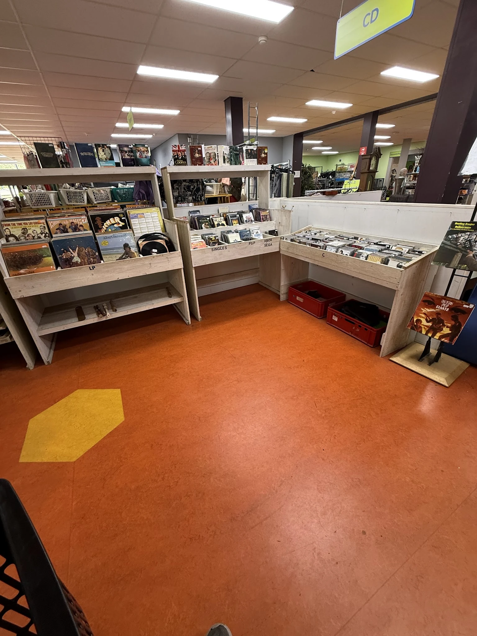 Winkelvloer met houten display kasten en rood-oranje vloer met geel markering