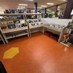 Winkelvloer met houten display kasten en rood-oranje vloer met geel markering