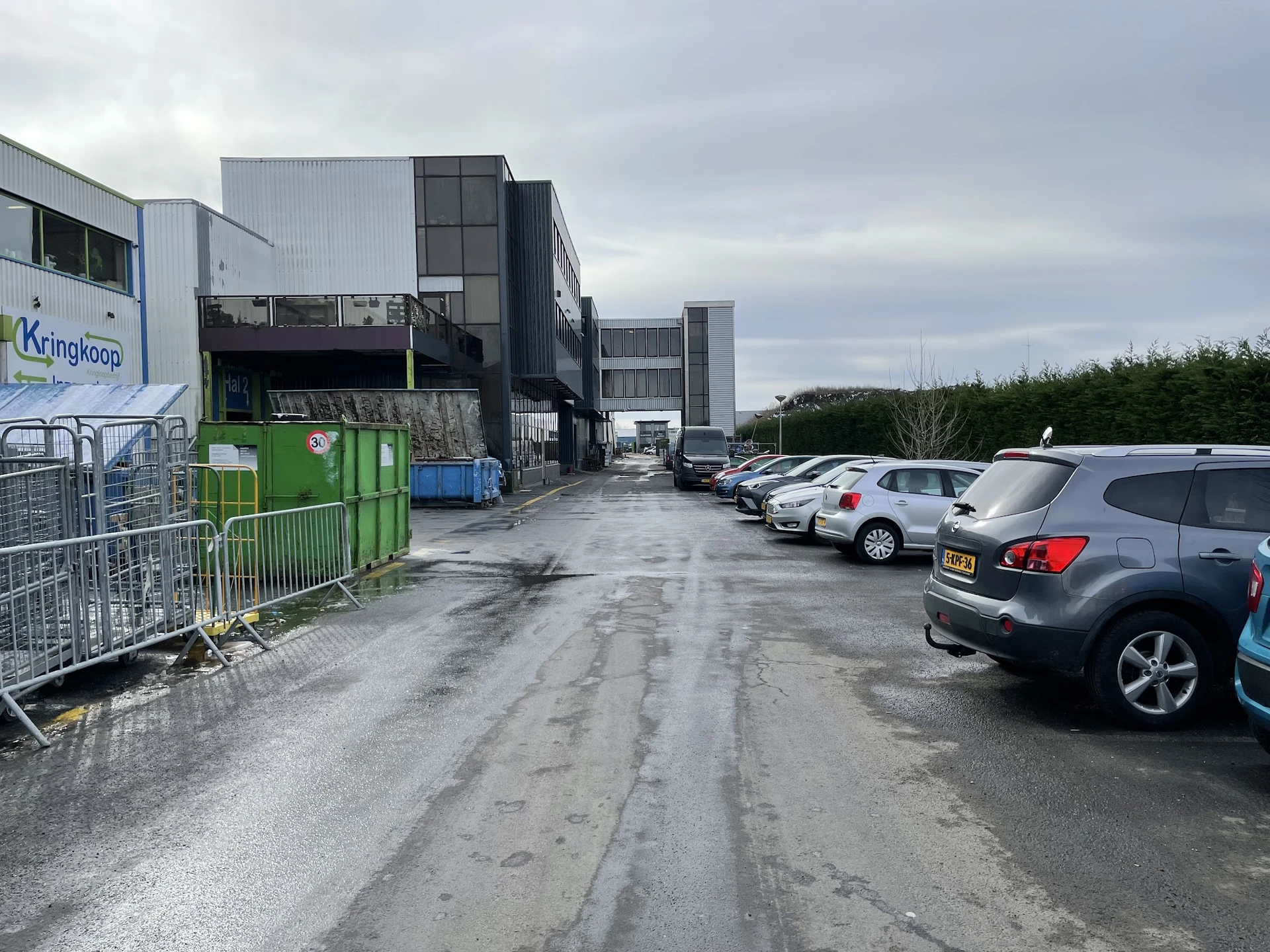Parkeerterrein met auto's voor industrieel pand van kringloopwinkel Kringkoop