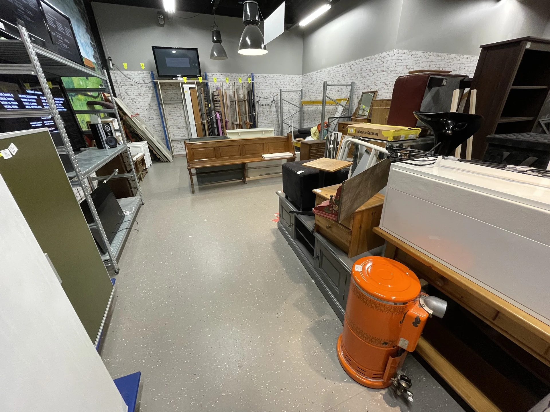 Winkelvloer met houten meubels, stellingen en diverse spullen in een kringloopwinkel
