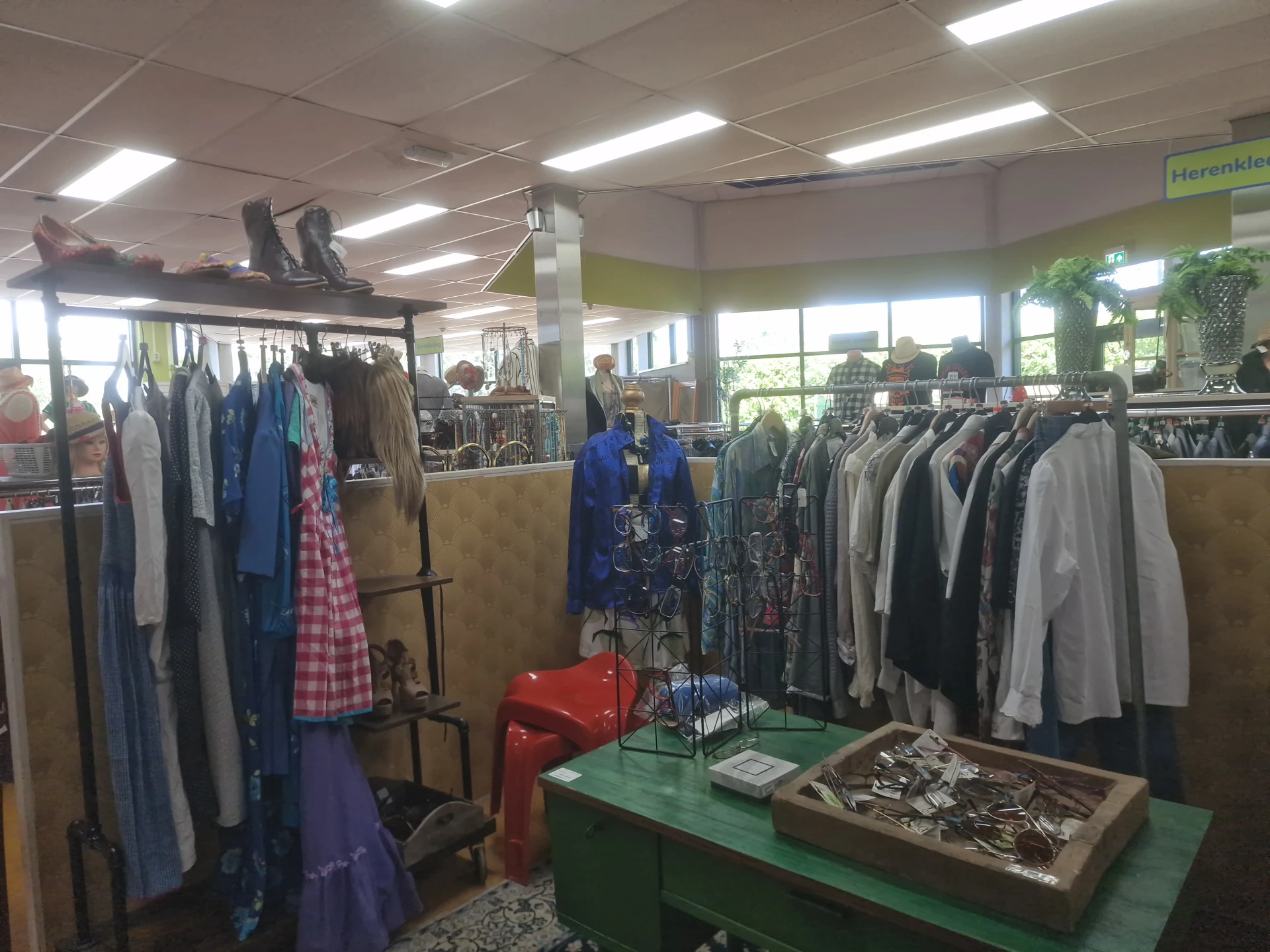 Rekken met tweedehands kleding, jassen en jurken in verschillende kleuren in de winkel