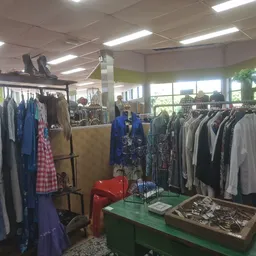 Rekken met tweedehands kleding, jassen en jurken in verschillende kleuren in de winkel