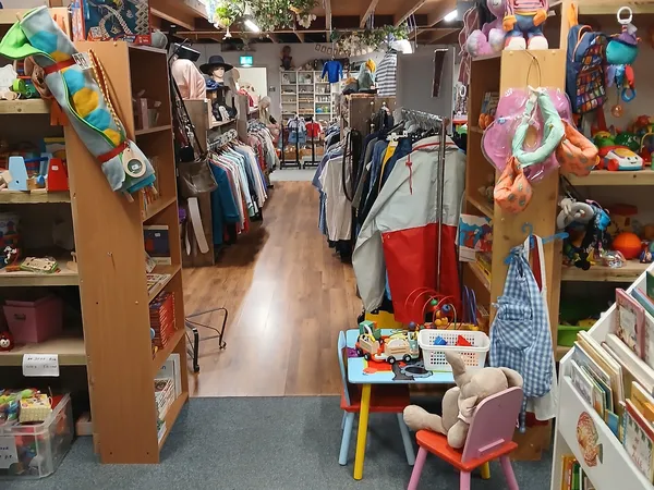 Winkelvloer van kringloopwinkel met kledingrekken, speelgoed, boeken en verschillende afdelingen