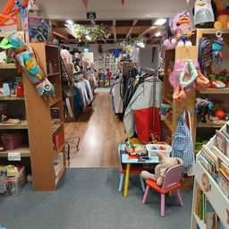 Winkelvloer van kringloopwinkel met kledingrekken, speelgoed, boeken en verschillende afdelingen