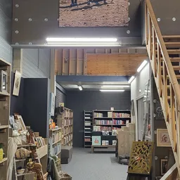 Binnenaanzicht van kringloopwinkel met boekenrekken, stellingen en tweedehands spullen onder LED-verlichting