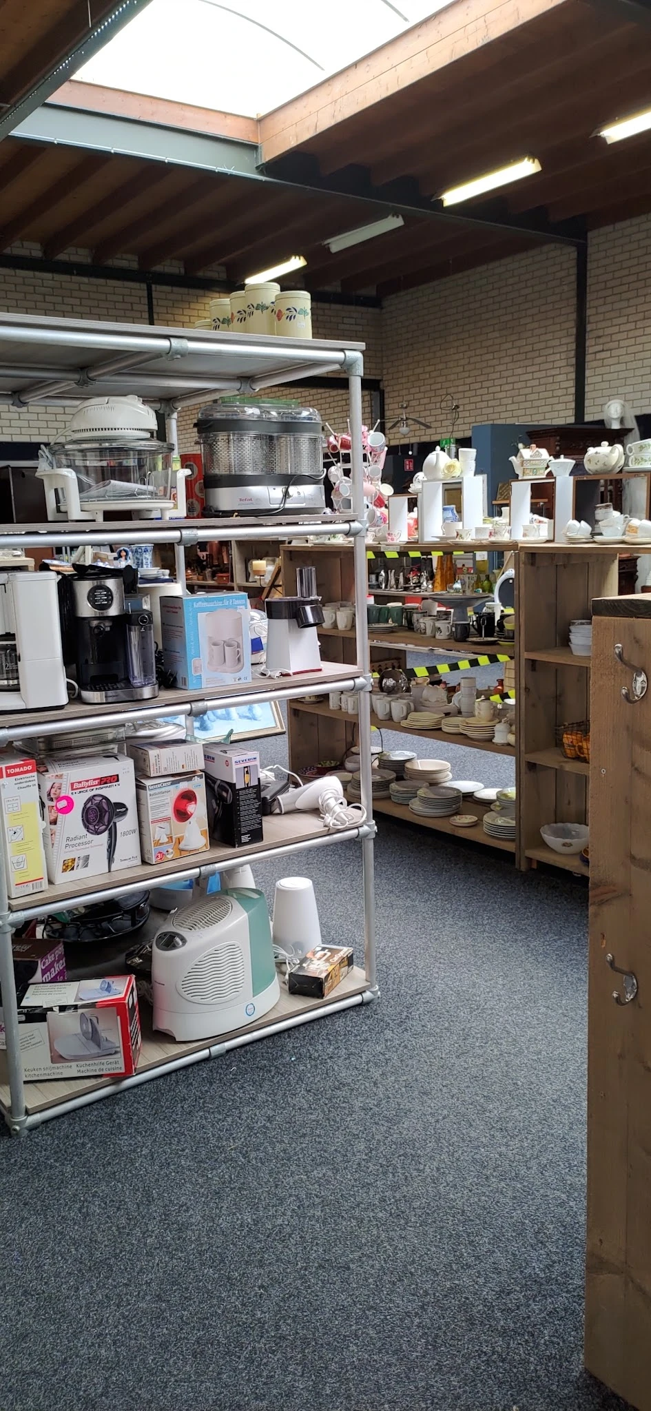 Stellingen met keukenartikelen, servies, huishoudelijke apparaten en diverse gebruiksartikelen in de winkel