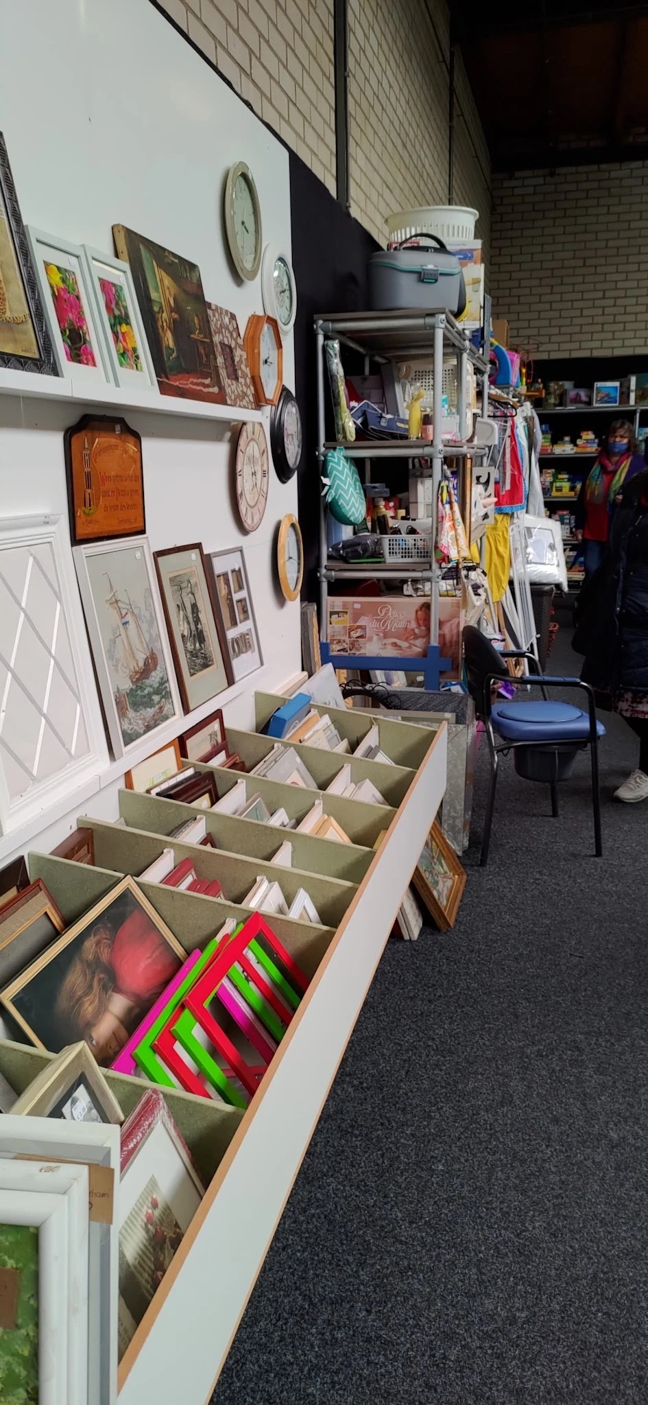 Groenkleurig sorteerkastje met gesorteerde boeken en schrijfwaren in vakken, op winkelvloer