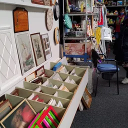 Groenkleurig sorteerkastje met gesorteerde boeken en schrijfwaren in vakken, op winkelvloer