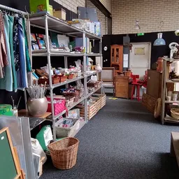 Winkelvloer met stellingen vol kleding, huishoudartikelen en diverse tweedehands spullen