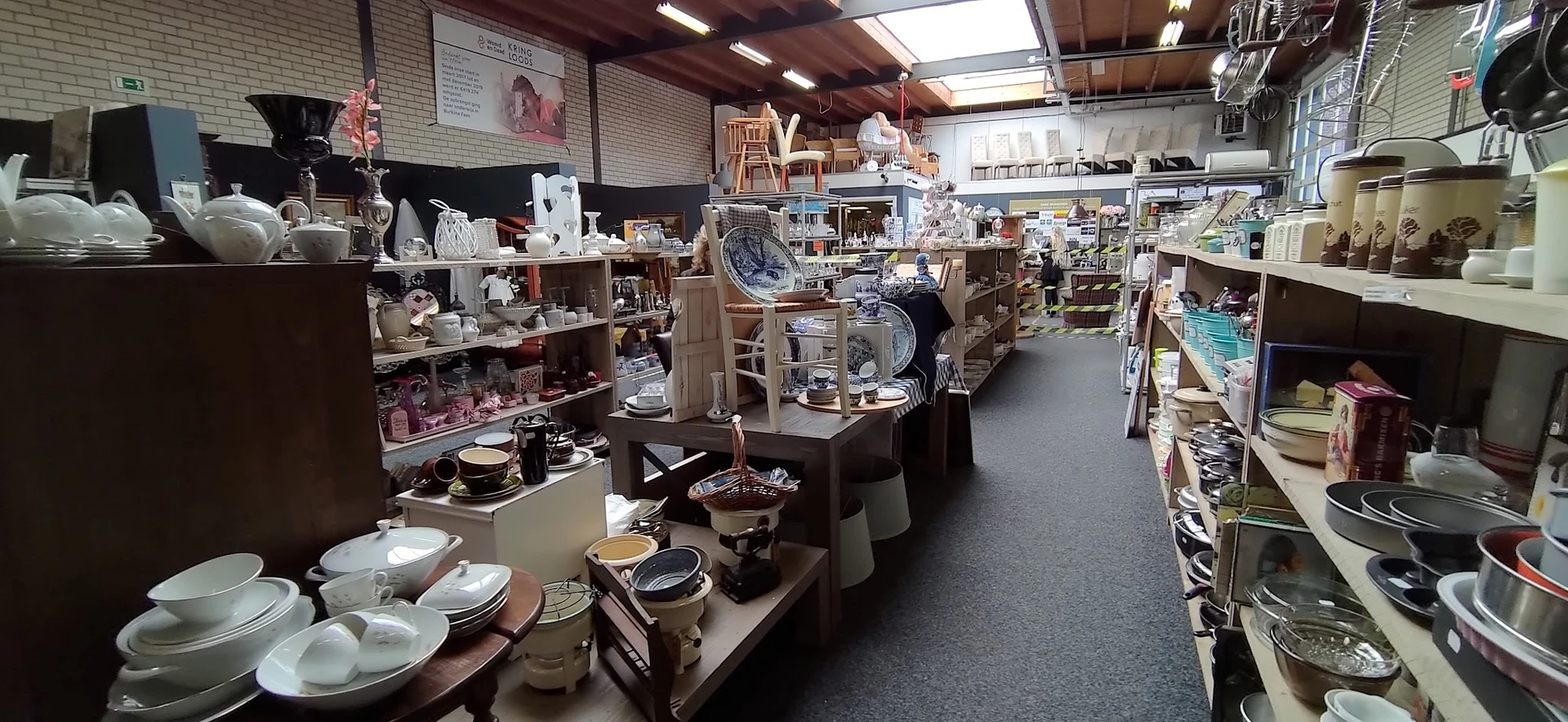 Winkelvloer met stellingen vol huishoudartikelen, servies, kookgerei en decoratie