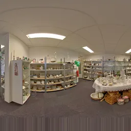 Panoramisch interieur van kringloopwinkel met stellingen vol serviesgoed, vazen en decoratieve items, witte wanden en plafond