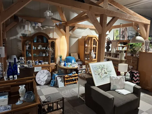 Ruim interieur van kringloopwinkel met houten balkenstructuur, meubels, kasten, decoratie en diversen huishoudartikelen
