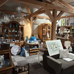 Ruim interieur van kringloopwinkel met houten balkenstructuur, meubels, kasten, decoratie en diversen huishoudartikelen