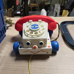 Vintage Fisher-Price telefoonSpeelgoed met rode hoorn, witte kunststof behuizing en blauwe wielen