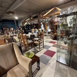 Winkelvloer van kringloopwinkel met meubels, stoelen, glazen vitrine en diverse huishoudartikelen