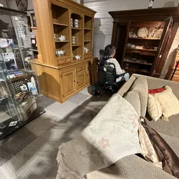 Winkelvloer met meubels, vitrines en een bezoeker in rolstoel