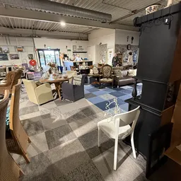 Winkelvloer met diverse meubels, stoelen, tafels en huisraad uitgestald in een kringloopwinkel