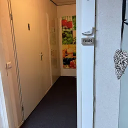 Gang met deuren naar verschillende afdelingen, waaronder toiletruimte, in een kringloopwinkel