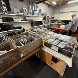 Tafels vol met tweedehands cd's, dvd's en elektronische apparatuur in kringloopwinkel